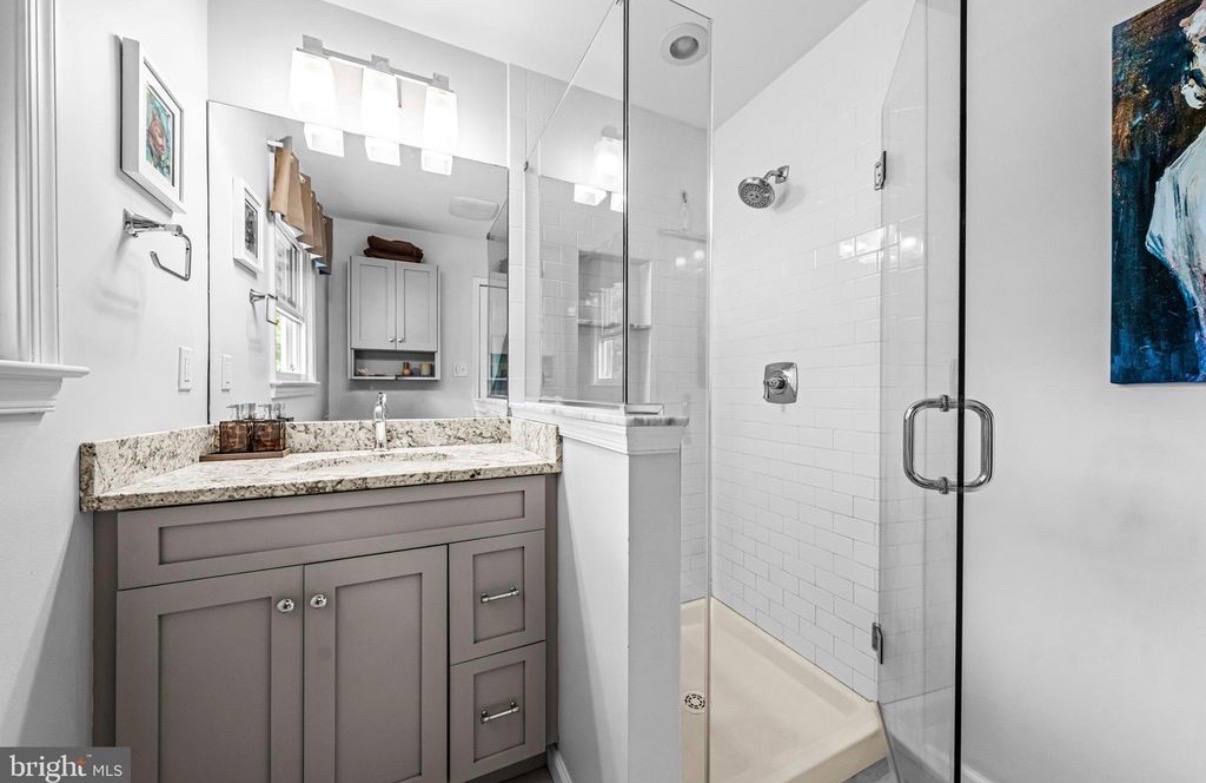 Remodeled hall bathroom in Doylestown PA with a tiled glass shower, granite top and grey shaker vanity
