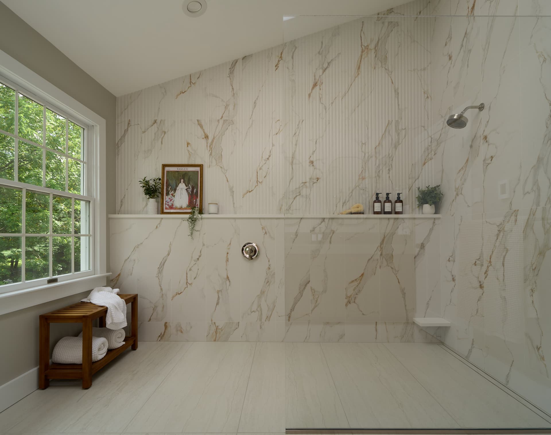 Curbless porcelain tile shower with a teak bench built into a primary bathroom remodel in Bucks County PA
